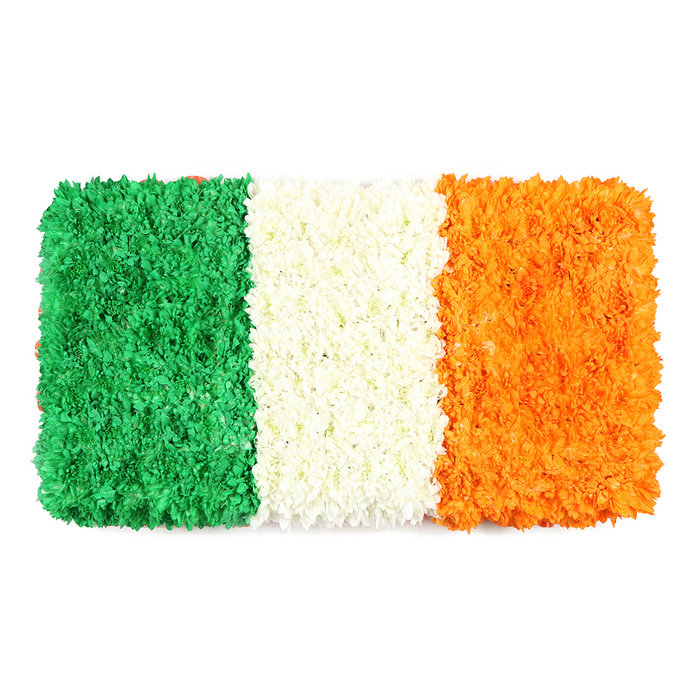 An aura of ceremony surrounds this rectangular floral flag, meticulously assembled to resemble the Irish Tricolour and set against a crisp white backdrop. The left stripe, a deep emerald green, is a dense field of tiny blossoms-likely green carnations or chrysanthemums-creating a verdant carpet with a pleasingly uneven, organic surface that catches the light and invites a closer look. The central white stripe appears almost ethereal, formed from closely grouped white petals that fuse into a soft, cloudlike band that separates the two sides with serene clarity. The right stripe shines in bright orange, its texture matching the green with the same careful pin-pointing of petals, giving the flag a sense of sunlit warmth and resolve. The leafless background emphasizes the vibrant colours while the three equal vertical panels maintain the flag's faithful proportions, a symbol of unity crafted with real floral hand and heart. The piece carries the scent of fresh petals and the memory of shared celebrations, ready to accompany St. Patrick's Day events, community gatherings, or a respectful tribute in the Golders Green area. The artistry reflects a local florist's experience, with each petal placed to convey meaning as much as beauty. Delivered to homes or venues around Golders Green, Temple Fortune, and surrounding streets, this artisanal banner of colour remains lively and fresh, a living emblem of heritage that can be enjoyed in windows, foyers, or reception spaces. Flowers Golders Green is proud to present a creation that speaks of national pride, peaceful coexistence, and the care that goes into every careful petal.
