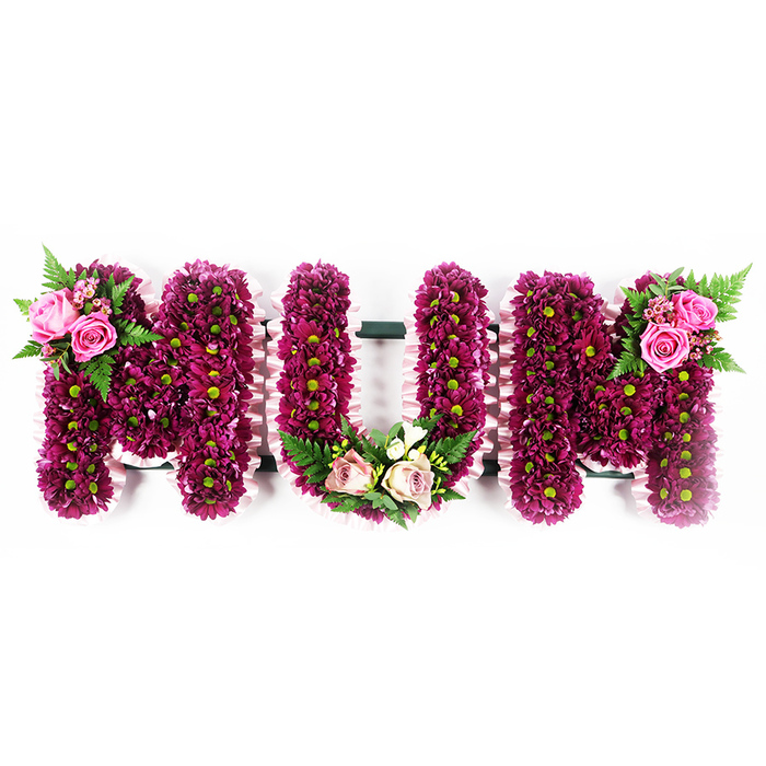 This image presents a graceful MUM funeral tribute, the letters standing out crisply against a pristine white background, much like a memorial display in a quiet chapel off Finchley Road. Each of the three large characters is crafted on a solid base, then lavishly covered with small fuchsia-purple to deep magenta spray chrysanthemums, packed so closely together they create a rich, textured surface. The flowers' subtle green centres provide a gentle contrast, dotting the design with soft, natural highlights. Around the outer sides of every letter runs a frill of pale pink ribbon, carefully pleated to form a delicate ruffle that frames the flowers and adds a feeling of softness and care. The first M is adorned on its upper left curve with an accent spray of soft pink roses, some fully open, others in bud, supported by airy green fern fronds that stretch gracefully outward. The U carries a more rounded embellishment at its base: lighter blush pink roses mingled with creamy white blooms reminiscent of freesia, interwoven with fresh fern foliage to trace a gentle U-shaped garland within the letter's curve. The second M echoes the first, bearing a complementary group of vibrant pink roses and lush green fern leaves on its upper right corner, ensuring visual balance across the tribute. The overall composition radiates quiet devotion and respect, a classic personalised sympathy arrangement often chosen in Golders Green to mark a beloved mother's life, whether for a funeral service, graveside gathering, or private remembrance at home.