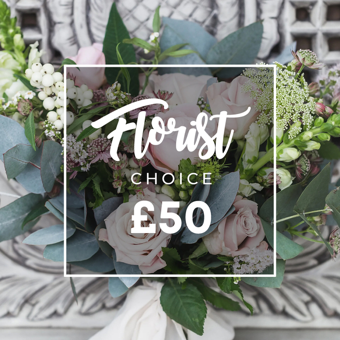 A lush, hand-tied bouquet sits before a softly blurred carved stone backdrop, the elegant setting echoing the arrangement's refined character. Dominant blush-pink roses form the heart of the design, their unfurling petals layered with delicate gradations from creamy blush to warm rose-each bloom feels like a quiet declaration of romance. Surrounding foliage is abundant and textural: rounded, dusty blue-green eucalyptus leaves breathe cool tones through the bouquet and create a graceful, sculptural frame; slender, upright green-and-white spikes add vertical energy at the edges; and tiny white filler flowers-perhaps waxflower or astrantia-give an airy, natural feel. Bright white berries, likely snowberries or hypericum, punctuate the composition with crisp, luminous spots that draw the eye. Hints of smaller, deeper pink or burgundy blooms nestle into shadowed pockets, providing contrast and depth. The stems are gathered and secured with a soft cream-coloured satin ribbon, its knot visible at the base and lending a bespoke, finished look. Overlaying the image is a clean rectangular frame with white typography indicating Florist in a flowing script and CHOICE beneath it, accompanied by a clear price marker-a visual cue that this is a curated florist's-choice bouquet. Captured in gentle daylight, the arrangement radiates calm sophistication and tactile promise: the velvet of roses, the crispness of berries, the cool silk of eucalyptus. Perfect as an elegant gift for birthdays, anniversaries, or as a thoughtful display at a Golders Green home-perhaps paired with a walk through nearby Golders Hill Park-this bouquet exemplifies considered craftsmanship and timeless floral beauty.