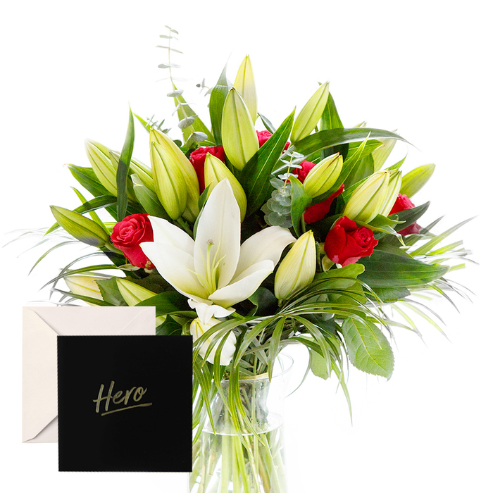 As a florist in Golders Green, I relish blending the bold with the serene, and this arrangement is a testament to that harmony. The white lilies drift at the heart of the bouquet, luminous and airy, their satin petals catching the soft morning light. They are beautifully contrasted by the tactile, lush greenery that encircles them: deep green fan leaves and wispy sprigs that whisper of quiet resilience. Rich ruby roses punctuate the design, their velvety petals a symbol of love and respect. The verdant leaves provide a cooling, forest-like backdrop, while a cluster of unopened lily buds suggests anticipation and new beginnings. In this gentle, natural light, the bouquet feels alive and uplifting-perfect for honoring someone's strength or celebrating a significant achievement on the Golders Green doorstep. The accompanying 'Hero' card makes this gesture feel both intimate and enduring, a touch of personal gratitude that resonates long after the moment passes. Available for same-day delivery across Golders Green and nearby NW11 communities, this arrangement brings a sophisticated warmth to any occasion-be it a milestone, a heartfelt thank you, or a tribute to a local hero who inspires others in our corner of London.