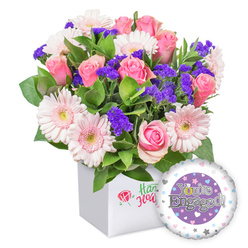 From a Golders Green storefront vantage, this joyful bouquet captures a deft balance of texture and color. Pink roses unfurl their petals in creamy spirals, exuding classic romance, while moonlit gerberas in subtle blush tones bring a light, airy lift to the arrangement. Deep purple statice peeks through, its saturated hue lending a surprising spark of depth and charm. Generous green foliage provides a lush, garden-fresh backdrop, guiding the eye through the composition and highlighting each bloom's gentle curvature. Set in a clean white square box with a restrained emblem-an understated red rose icon paired with green script-the presentation feels refined and thoughtful. A round balloon sits to the lower right, its central purple panel bearing the engraved message You're Engaged! in polished silver letters, with a gleaming golden O in You're adding a touch of sparkle. The outer ring hosts tiny pastel hearts and silver stars, echoing the celebratory mood of a couple taking a new step. This arrangement radiates happiness, warmth, and optimism for the journey ahead, a perfect congratulatory gift for an engagement. Flowers Golders Green offers reliable same-day delivery across Golders Green, Cricklewood, and Hendon, ensuring the moment is shared quickly with loved ones living nearby.