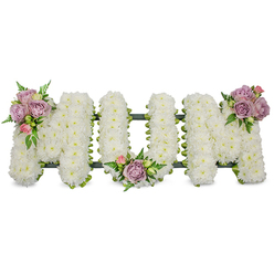A carefully sculpted floral tribute spells the word MUM in large, capital letters, each letter densely covered with hundreds - perhaps thousands - of pristine white chrysanthemums or similar petite white blooms that give a soft, cloud-like texture under gentle light. The clean white surface reads as a symbol of purity and peace, its compact petals forming a uniformly luminous field that seems almost tactile. Accenting the crisp white are three small, artful clusters of pastel blooms: soft lavender roses with their powdery lilac tones, blush-pink rosebuds both closed and half-open, and fresh green leaves with delicate fern-like fronds that add movement and a cool, botanical scent. One cluster rests on the upper left arm of the first 'M', another nestles in the low curve of the 'U', and a third highlights the upper right arm of the final 'M', creating a considered, triangular balance. A dark green structural frame - possibly ribbon-wrapped or moss-covered - is visible beneath the flowers as a subtle outline and base, ensuring the letters stand with dignity and shape. The arrangement conveys quiet remembrance and deep affection, a traditional sympathy piece suitable for service, chapel, or graveside. As a local Golders Green florist would observe, the restrained palette and classic form are commonly chosen by families from surrounding streets such as Golders Green Road and Finchley Road, where soft pastels and clean whites are preferred for commemorating a mother with gentle, understated grace.