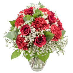 A classic red and white bouquet stands proudly in a clear glass vase, photographed against a clean white backdrop so that every flower and leaf appears vivid and distinct. At the centre, rich crimson red roses draw the eye, each bloom layered with velvety petals curling inwards in perfect spirals, evoking deep affection and enduring love. Nestled closely around them, red carnations with intricately ruffled petals create a plush, cushion-like texture, giving the arrangement a rounded, abundant shape that feels generous and comforting. Between these bold red blossoms, delicate sprays of white baby's breath (Gypsophila) drift through the design like tiny clouds, softening the intensity of the colour and adding a sense of lightness and purity. Fresh greenery, including glossy dark rose leaves and softly rounded eucalyptus, brings calm balance and a gentle woodland fragrance, reminiscent of the leafy streets and gardens dotted around Golders Green. The stems are clearly visible through the transparent vase, resting in clear water at the base, a subtle sign of professional care and attention from an experienced local florist. Bright, even lighting enhances the natural sheen of the petals and the fine texture of the foliage, casting minimal shadows and keeping the focus squarely on the vibrant blooms. The overall mood is romantic yet dignified, ideal for sending to a partner or family member in Golders Green to mark an anniversary, celebrate a special milestone, or simply brighten a quiet evening at home near Golders Green station with a heartfelt gesture of love and appreciation.