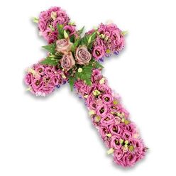 This photograph shows a stately floral cross, designed as a tribute for times of loss, set against a bright white background that throws every subtle hue into relief. The cross appears sturdy yet tender, its entire surface hidden beneath layers of blossoms in harmonious shades of pink, mauve, and gentle lilac. At the central junction, three fully open roses in a quiet dusty-rose and muted mauve tone sit side by side, their spiralled petals overlapping to create a rounded focal area that feels warm and intimate. Around this cluster, airy fern fronds and neat, medium-sized green leaves arch softly, providing both texture and a cool counterbalance to the soft floral colours. Stretching outward along the horizontal arms and down the vertical stem, the arrangement is heavily adorned with lisianthus and trumpet-shaped flowers in a range of pinks, some blooms showing darker throats or edges that lend depth. Little pockets of fine pink and lavender filler flowers, delicate white blooms, and small pale green buds are tucked between the main heads, giving the design nuance and movement. At the periphery, slim flashes of deep purple ribbon or structural fabric can be glimpsed beneath the petals, tracing a refined outline. The mood is peaceful and reverent, suggestive of a piece that could be delivered by Flowers Golders Green for a funeral or memorial service around Golders Hill Park or a quiet synagogue on nearby streets, providing a soft, floral expression of sympathy, hope, and enduring love.