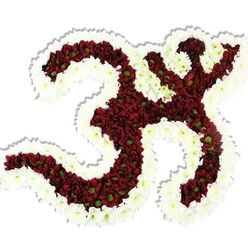 There is immediate artistry in the way each curve of the Om symbol has been rendered from living flowers: dark red, almost maroon chrysanthemum-like heads packed so densely they read as plush velvet, each punctuated by a small lime-green centre that gives the interior a heartbeat of contrast. A thick, undulating rim of pure white spray chrysanthemums frames the symbol, tracing its distinctive '3' curve, downward stroke and crescent with a clarity that makes the icon feel both ancient and freshly crafted. Against a plain white background the arrangement reads like a devotional relief - the flowers' layered petals catching soft, even light and throwing a subtle drop shadow that defines volume and solidity. As a local florist would note, the texture is tactile in imagination: petals cool to the touch, slightly foxed with late-season spice, a gentle vegetal perfume that calms the room. The composition's scale and fullness give it a sculptural presence suited to memorial settings or spiritual celebrations: a centrepiece for a satsang, a tribute at a remembrance service, or an altar offering. For customers in Golders Green, from Hoop Lane to the streets around Golders Hill Park, this piece feels pertinent and place-aware - a design that honours ritual, invites quiet reflection, and demonstrates meticulous floral craftsmanship without overwhelming the solemnity of the occasion.