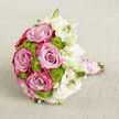 Laid gently on a pale, oatmeal-toned cloth that shows a subtle linen-like weave, this hand-tied bouquet looks ready to be lifted by a bride stepping out of a car near Golders Green station. The arrangement is built around generous pink roses, each in full bloom, their layers of petals shading from a delicate powder pink inside to a more saturated, almost magenta hue along the outer curls. These roses create a romantic core, rich in texture and soft shadow, like little whirlpools of colour. Nestled between them are rounded cushions of lime-green button chrysanthemums, their minute, tightly clustered petals forming tidy spheres that bring a vivid, zesty green to the design. On the right, a spray of white lisianthus unfurls with ruffled, paper-thin petals; some flowers are open and fluttering, others remain as slender buds tinged with cream, adding a sense of movement and anticipation. The stems are bound into a smooth handle, wrapped in a blush satin ribbon that reflects light with a gentle sheen, reminiscent of a bridesmaid's dress at a local synagogue celebration. Encircling the ribbon, delicate strands of white pearls are coiled in precise loops, lending a classic, heirloom feel that suits registry weddings and hotel receptions around Golders Green. The neutral background fabric, with its understated crosshatch texture, frames the bouquet without distraction, allowing every nuance of pink, green, and white to stand out clearly. This floral design conveys softness and joy, as if capturing the quiet excitement of a wedding morning, when perfume, silk, and fresh flowers fill a Golders Green townhouse with promise.