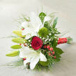 Arranged on a neutral, linen-like surface the colour of warm cream, this bouquet appears as though it has just been placed down by a florist's careful hands in a quiet Golders Green studio. The main focus is a cluster of white oriental lilies, their trumpet-shaped blooms unfolding with poise. Some petals curl gracefully outward, revealing faint russet speckles deep at the centre, while nearby buds remain closed, sheathed in pale green, suggesting a design that will evolve beautifully after delivery. At the heart of the bouquet, a single deep red rose forms a perfect spiral, each velvety petal tightly layered, imparting a sense of unwavering affection that would suit a wedding at a local venue off Finchley Road or a private celebration near Hampstead Garden Suburb. Two bright green 'Green Trick' dianthus spheres introduce an unexpected, almost moss-like texture, giving the arrangement a fresh, contemporary twist. Scattered delicately throughout, airy sprays of white gypsophila lighten the design, like a soft veil of stars threading through the lilies and rose. Clusters of glossy red hypericum berries add small, jewel-like accents, mirroring the rose's ruby hue and providing a hint of festive cheer. Rich green foliage fans outward, combining broad, structured leaves with slender, feathery stems that give the bouquet gentle movement and a sense of breath. Binding it all, a luxurious red satin ribbon wraps the stems, its sheen catching the light where the tied end rests toward the bottom right. The entire composition, reminiscent of the refined wedding flowers often requested from local Golders Green florists, radiates romance, elegance, and quiet celebration, ideal for an anniversary, engagement, or bridal bouquet with local same-day delivery.