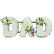 A carefully crafted funeral tribute formed into three upright, three-dimensional block letters spelling DAD, each letter densely packed with hundreds of small, pristine white chrysanthemums and similar button-style blooms that together create a plush, cloud-like surface. A narrow band of fresh, emerald-green satin ribbon runs around the outer edge of every letter, its subtle sheen catching soft daylight and crisply defining each shape against the bright white background. The letters sit on a discreet dark support frame visible as horizontal bars behind them, indicating the piece is designed to stand for display at a service or graveside. The arrangement is gently enlivened with floral accents: the upper left curve of the first D is softened by a small cluster of delicate white freesia and glossy green foliage, while two long, sinuous green stems arch across from the top of that D toward the central A. Where those stems meet a composed spray at the A, two deep purple calla lilies rise in trumpet-shaped elegance, their velvety petals offering a solemn contrast to the snowy whites. The final D carries a complementary cluster of white freesia and leaves on its upper right, balancing the composition. There is a quiet scent of freesia and fresh greenery, and a tactile impression of softness and care-an understated, dignified tribute intended for a beloved father. Locally, this style of memorial is often chosen for services at Golders Green Crematorium or wakes in nearby Temple Fortune and Childs Hill, where families seek a personal, respectful floral message of love and loss.