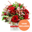 Against a crisp white background, a generous, dome-shaped bouquet in passionate shades of red and lush green sits proudly in a clear glass vase, as if waiting on a Golders Green mantelpiece or windowsill. At the core of the design, velvety red roses in various stages of opening form a striking centre, their petals rich and smooth, some still tightly wrapped, others unfurled to showcase their layered, romantic hearts. Between these signature blooms are smaller deep red flowers, reminiscent of alstroemeria with their multiple petals and subtly variegated tones, which contribute texture and depth. Fine sprays of tiny pale pink and white blossoms, similar to waxflower, are scattered throughout the arrangement, introducing a gentle, airy contrast that keeps the composition from feeling too heavy. A wide collar of greenery surrounds the flowers, blending glossy dark green leaves with fresher, lighter sprigs to create a natural frame. Among this foliage, distinctive burgundy and reddish-brown leaves with understated veining add a touch of drama and sophistication, like the darker tones of mature trees around nearby Golders Hill Park. The bouquet is neatly arranged in a modern, clear rectangular glass vase, the straight lines and visible stems contributing to a contemporary feel that would suit North West London townhouses and apartments. A red ribbon circles the vase, patterned with small white heart outlines that underscore the loving sentiment of the design without overwhelming it. In the lower right corner, an eye-catching circular orange graphic bears the bold white message VASE INCLUDED, clearly signalling that this romantic floral gift is ready to display on arrival, ideal for anniversaries, Valentine's surprises, or expressing heartfelt affection to someone in Golders Green.